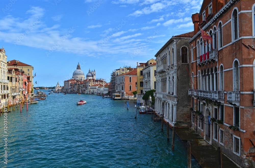 panoramic view of the wide Venetian canal, with the domes of the Basilica Della Salute in the background