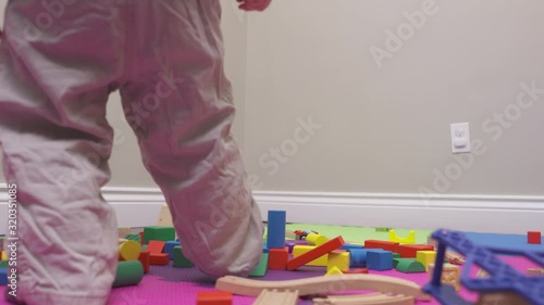 Toddler kicks a tower of blocks and knocks them over.