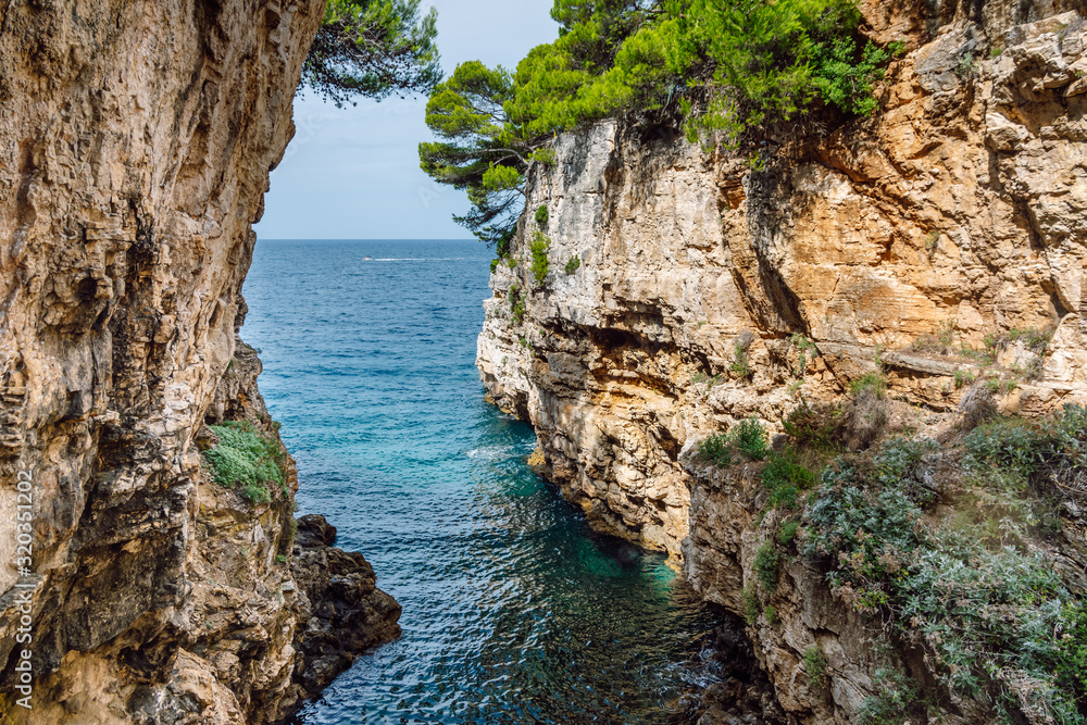 A paradise sea canyon with high sheer cliffs descending to turquoise  water, Verudela Canyon, Pula, Croatia.