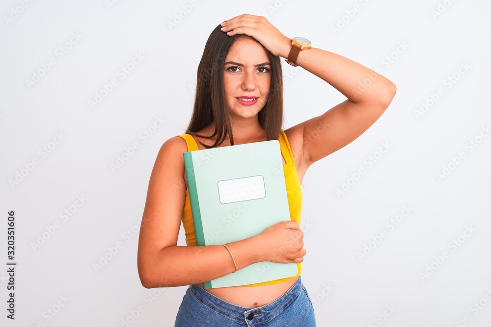 Young beautiful student girl holding notebook standing over isolated white background stressed with hand on head, shocked with shame and surprise face, angry and frustrated. Fear and upset Young beautiful student girl holding notebook standing over isolated white background stressed with hand on head, shocked with shame and surprise face, angry and frustrated. Fear and upset