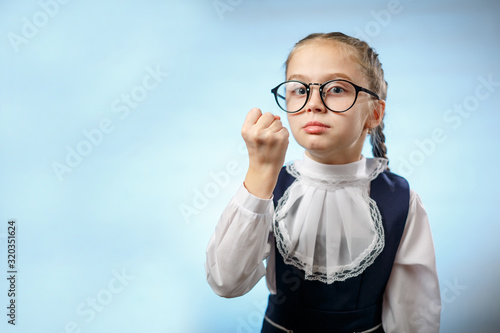 Cute Primary Schoolgirl Make Fist Blue Background