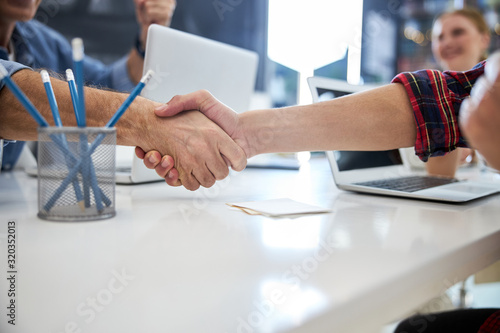 Business partners shaking hands during meeting in office