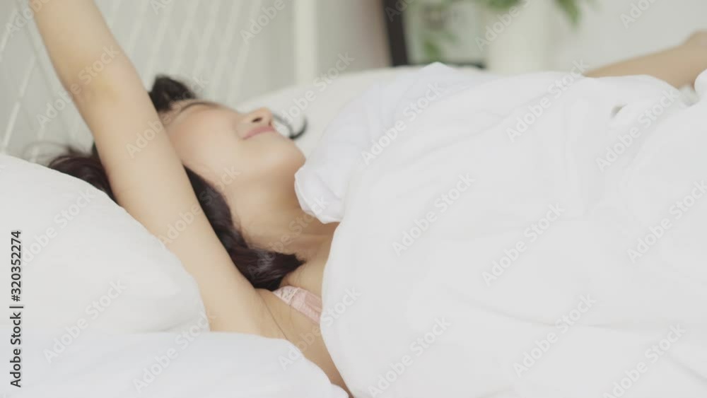Beautiful young asian woman waking up in the morning with happy and stretching on bed in the bedroom, girl sleep comfort and awake and relax with cosy in bedchamber, wellbeing and health concept. Beautiful young asian woman waking up in the morning with happy and stretching on bed in the bedroom, girl sleep comfort and awake and relax with cosy in bedchamber, wellbeing and health concept.
