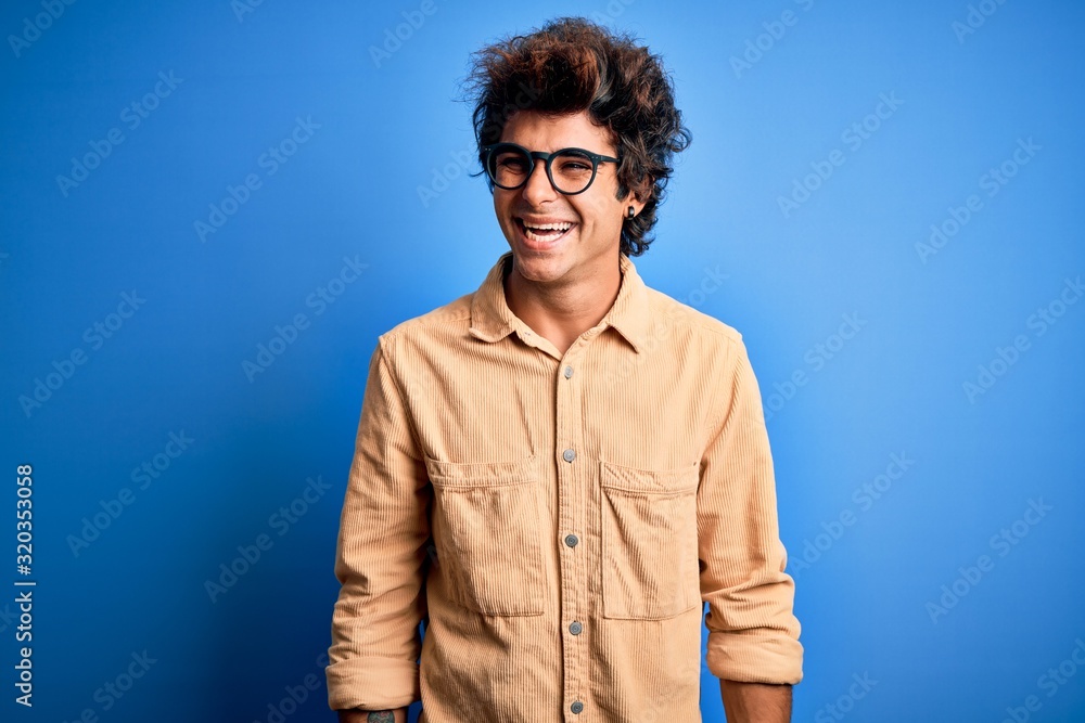 Young handsome man wearing casual shirt standing over isolated blue background looking away to side with smile on face, natural expression. Laughing confident. Young handsome man wearing casual shirt standing over isolated blue background looking away to side with smile on face, natural expression. Laughing confident.
