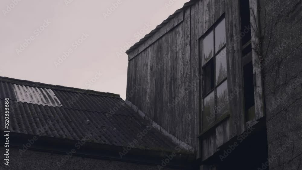 Wet day raining on abandoned farm courtyard. Quiet and eerie. Farm objects and equipment sit silent. Grey weather. Old buildings, stables and walkways. Wet day raining on abandoned farm courtyard. Quiet and eerie. Farm objects and equipment sit silent. Grey weather. Old buildings, stables and walkways.