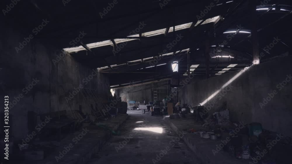 Dark abandoned farm building with light beaming through holes in walls and roof. Scary, eerie dark shadows. Cobwebs and dust cover random objects. Dark abandoned farm building with light beaming through holes in walls and roof. Scary, eerie dark shadows. Cobwebs and dust cover random objects.