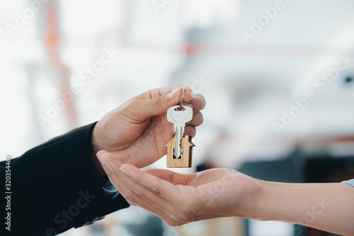 Real estate agent  holding key with house shaped keychain. photo