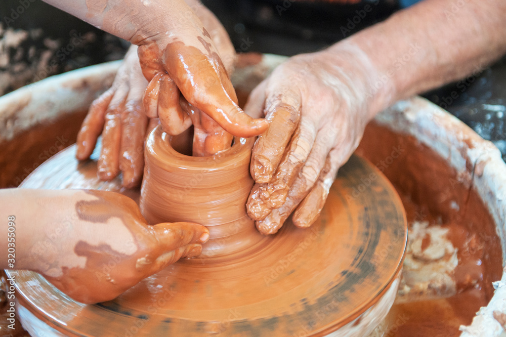 The potter makes pottery dishes on potter's wheel.