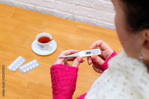 Sick woman holds a thermometer in her hands
