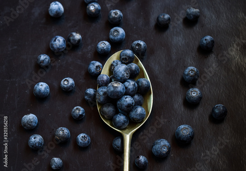 metal spoon whit blueberries on a dark base