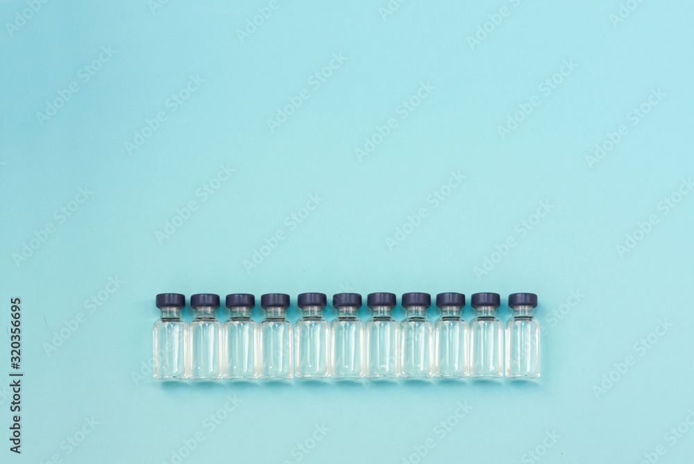 Medicine in vials, ready for vaccine injection on blue background. Horizontal composition. Front view.