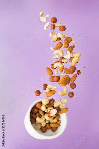 Flying nuts on a purple background: almonds, cashew and hazelnat photo