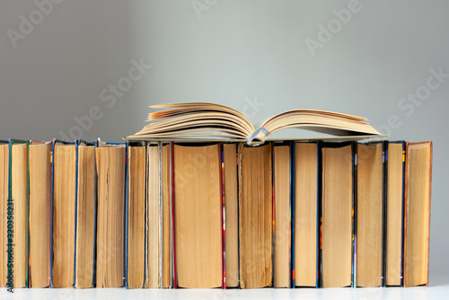 Open hardback book  diary  fanned pages on stack of books on white table in library. Books stacking. Back to school concept. Copy Space. Education learning background.
