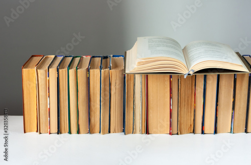 Open hardback book, diary, fanned pages on stack of books on white table in library. Books stacking. Back to school concept. Copy Space. Education learning background.