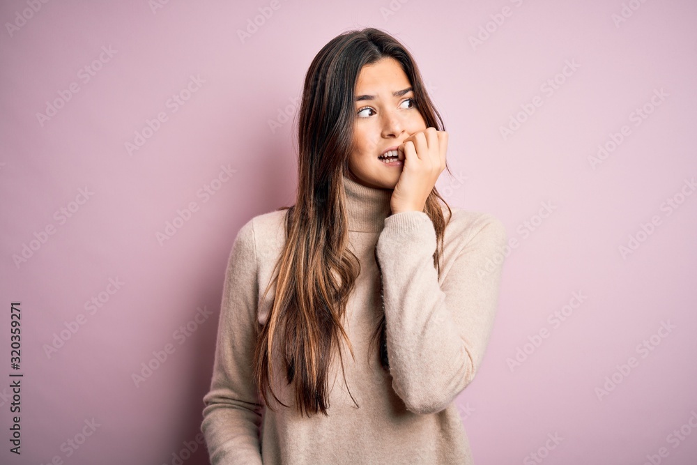 Young beautiful girl wearing casual turtleneck sweater standing over isolated pink background looking stressed and nervous with hands on mouth biting nails. Anxiety problem. Young beautiful girl wearing casual turtleneck sweater standing over isolated pink background looking stressed and nervous with hands on mouth biting nails. Anxiety problem.