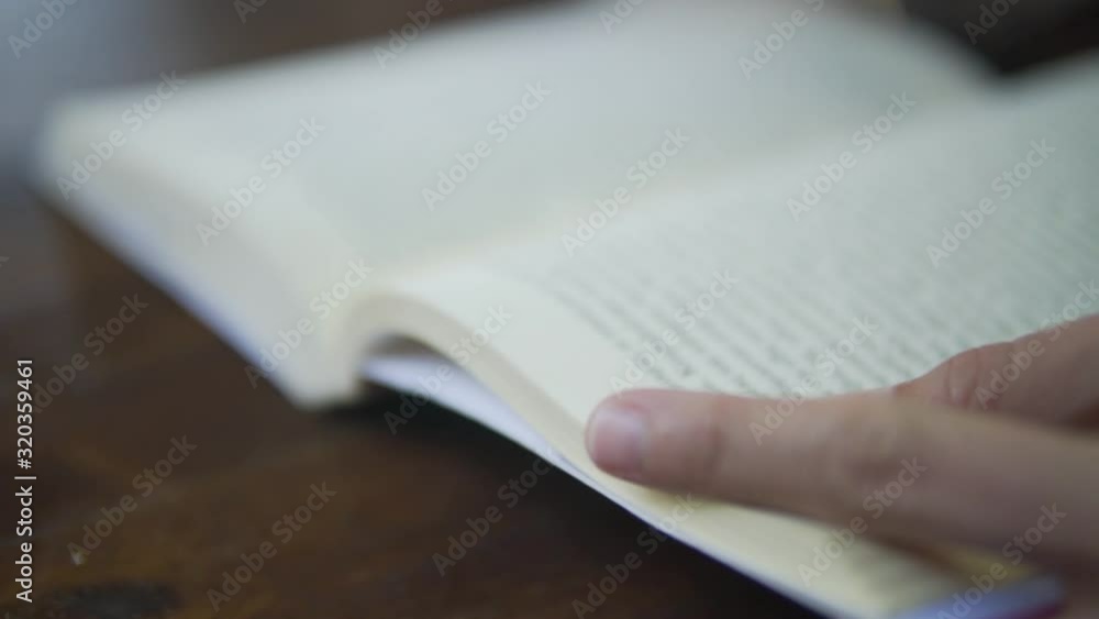 close up of caucasian person reading a book while sitting on table, relaxing with a book, personal time , free time studying  b roll
