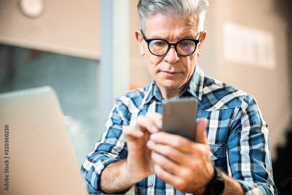 Mature man in glasses holding mobile phone in hands Mature man in glasses holding mobile phone in hands