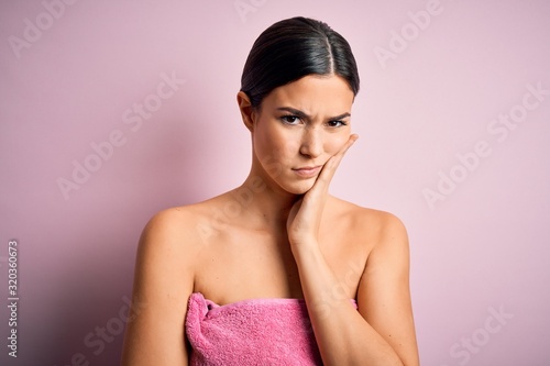 Obraz na płótnie Young beautiful girl wearing towel shower after bath standing over isolated pink background thinking looking tired and bored with depression problems with crossed arms