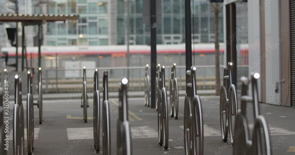 custom made wallpaper toronto digitalCinematic medium wide 4K shot with slow parallax motion of illuminated steel bicycle parking stands and train leaving the central train station in overcast daylight, in Barcode Bjørvika Oslo Norway.