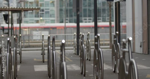 Wallpaper Mural Cinematic medium wide 4K shot with slow parallax motion of illuminated steel bicycle parking stands and train leaving the central train station in overcast daylight, in Barcode Bjørvika Oslo Norway. Torontodigital.ca