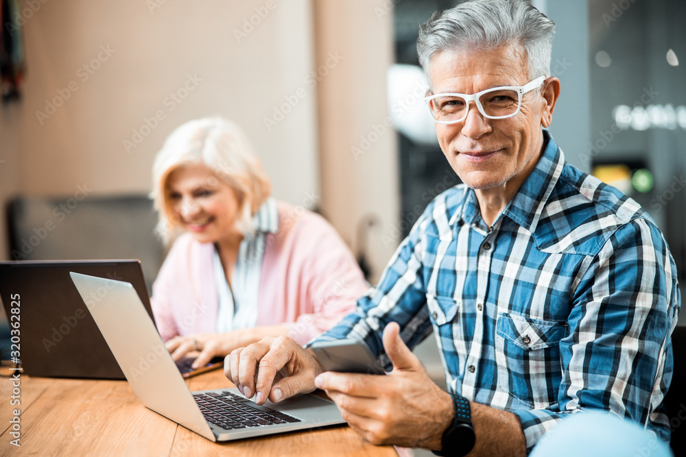 Happy mature male holding smartphone while working Happy mature male holding smartphone while working