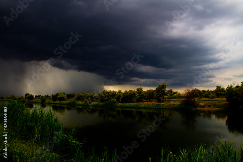 The approach of a thunderstorm with a shower over the river