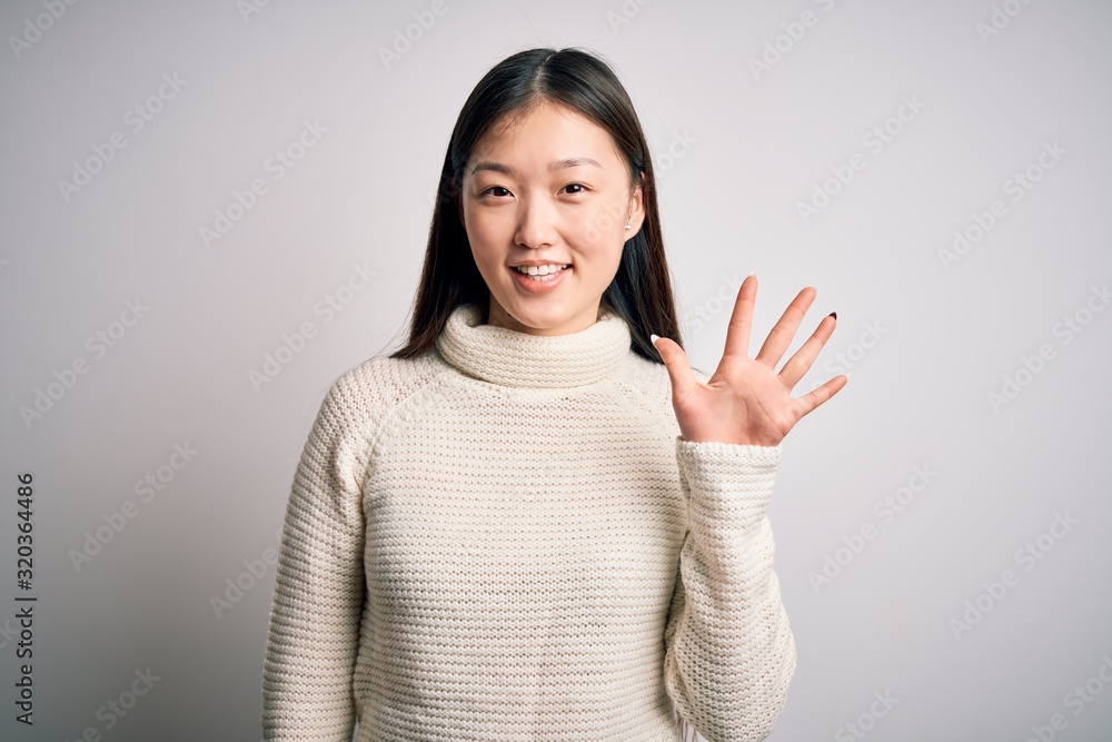 Young beautiful asian woman wearing casual sweater standing over isolated background showing and pointing up with fingers number five while smiling confident and happy. Young beautiful asian woman wearing casual sweater standing over isolated background showing and pointing up with fingers number five while smiling confident and happy.
