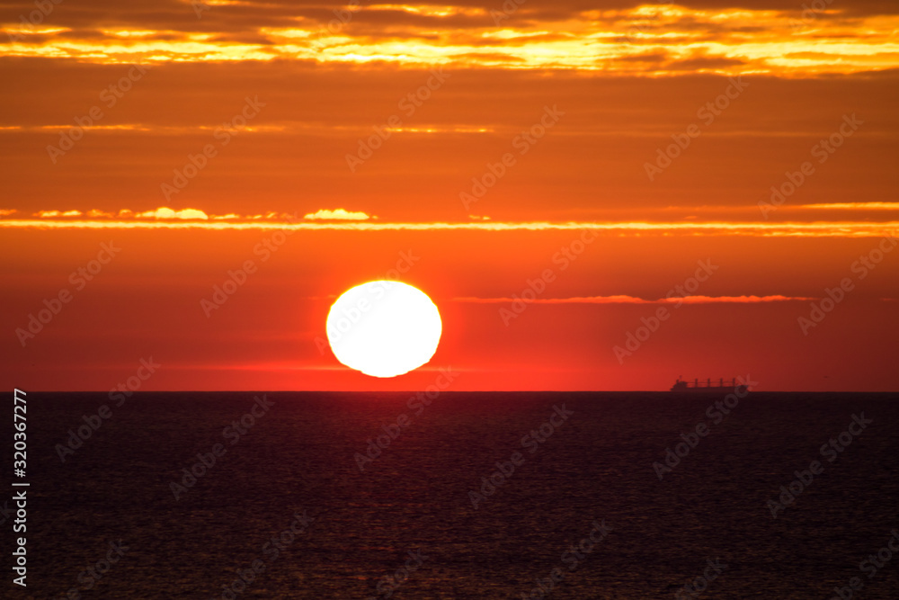 close-up of red sunrise at the sea, ship on the horizon