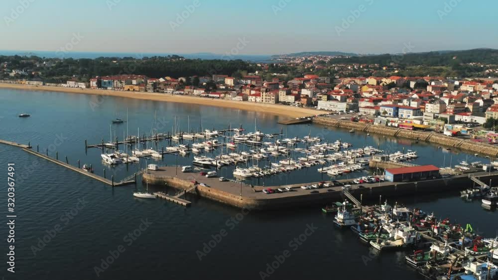 Fisher boats in Pobra do caraminal, aerial view of harbor, coast road and town. Slow pan right, beautiful Galicia Spain coastline, sunny bright day. Fisher boats in Pobra do caraminal, aerial view of harbor, coast road and town. Slow pan right, beautiful Galicia Spain coastline, sunny bright day.