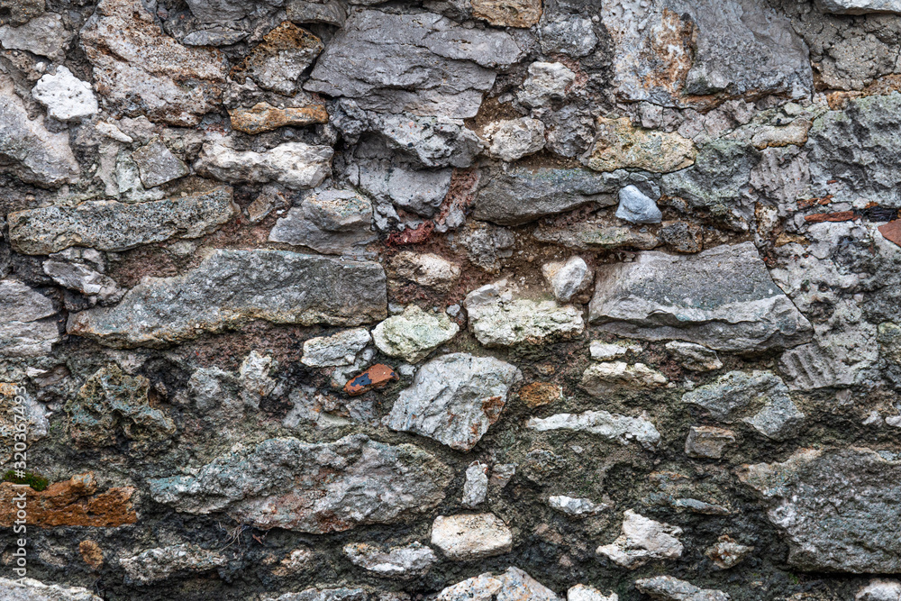 wall composed of large exposed stones with grey cement