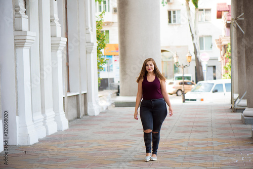 Pretty young woman walking on the city street. Casual fashion, plus size model. xxl women on nature.