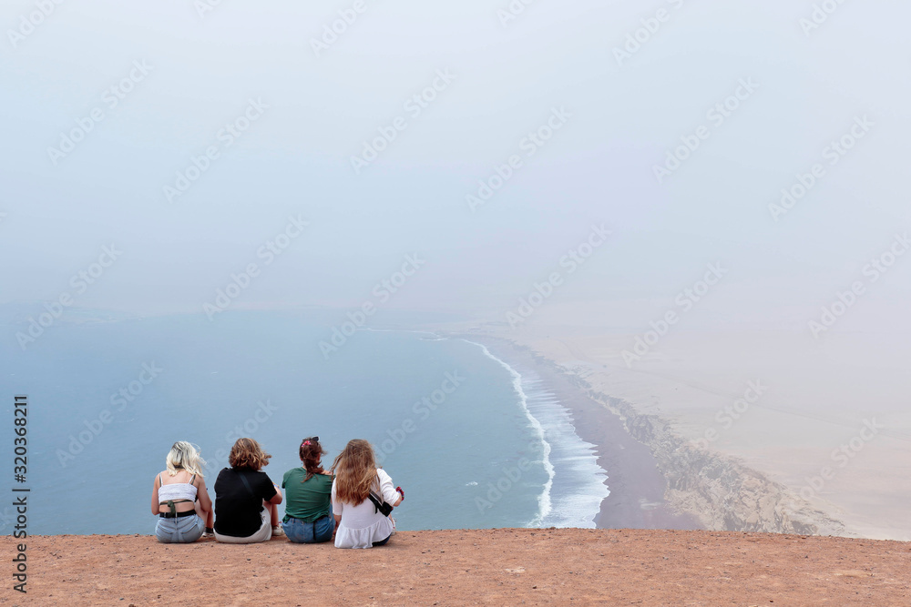 Women contemplating beautiful view from the viewpoint of Isthmus II, in Paracas, from where you can see the beach and the horizon. Ica-Peru