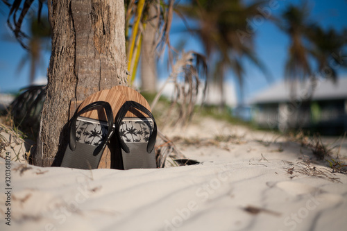 Flip flops on a beautiful sunny beach in a tropical location with blue sky and palm trees