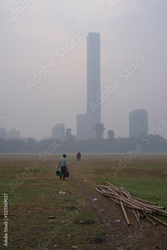 Local Indian people are walking in a dry grass field in a misty winter morning in natural background. Indian lifestyle.