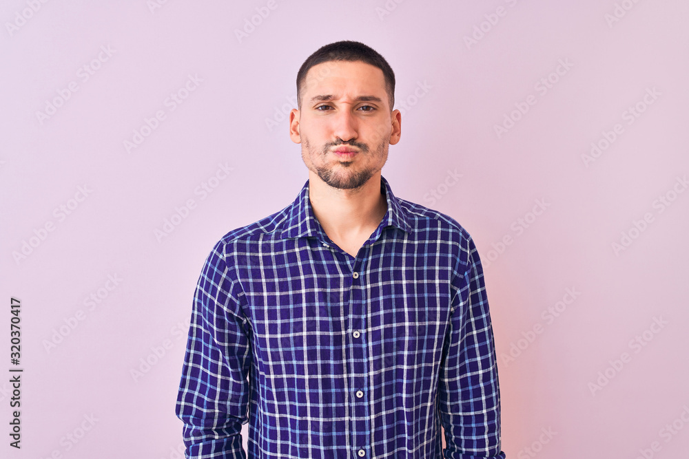 Young handsome man standing over isolated background puffing cheeks with funny face. Mouth inflated with air, crazy expression. Young handsome man standing over isolated background puffing cheeks with funny face. Mouth inflated with air, crazy expression.