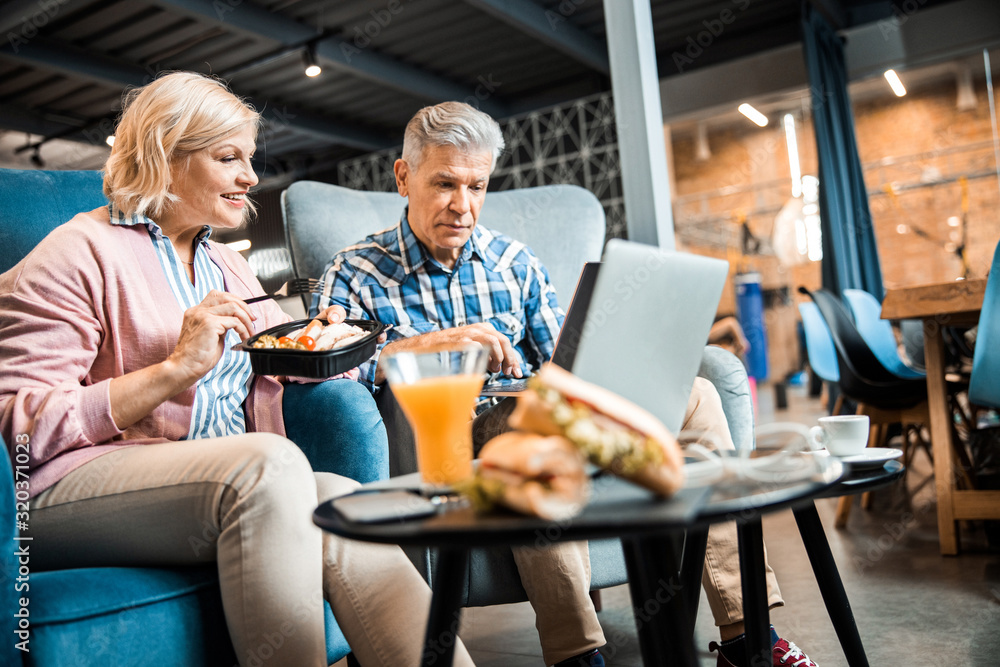 Smiling adult lady sitting next to man while eating food Smiling adult lady sitting next to man while eating food