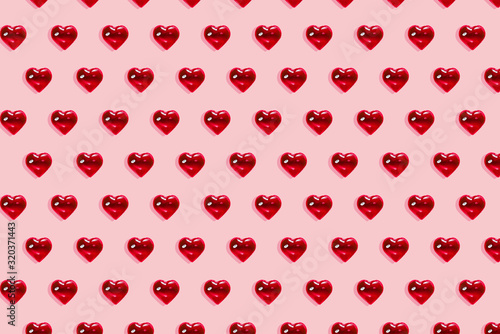 Valentine's day background. Pattern of glass red hearts on a pastel pink background. Card minimalism, Symbol of love