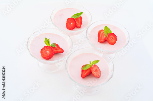 delicate strawberry ice cream with slices of strawberries with cream in a glass bowl on a light background, for advertising confectioners or sweets