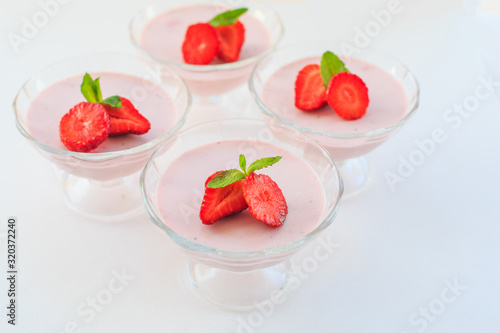 delicate strawberry ice cream with slices of strawberries with cream in a glass bowl on a light background, for advertising confectioners or sweets