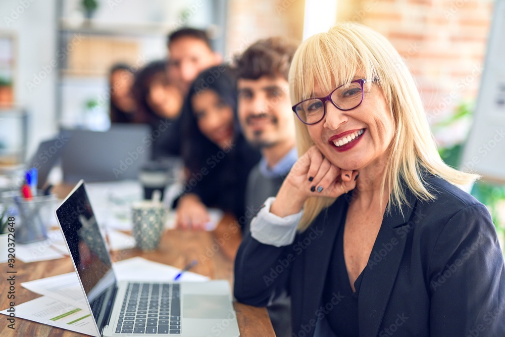 Group of business workers sitting in line with smile on face. Looking at the camera, middle age woman smiling at the office Group of business workers sitting in line with smile on face. Looking at the camera, middle age woman smiling at the office