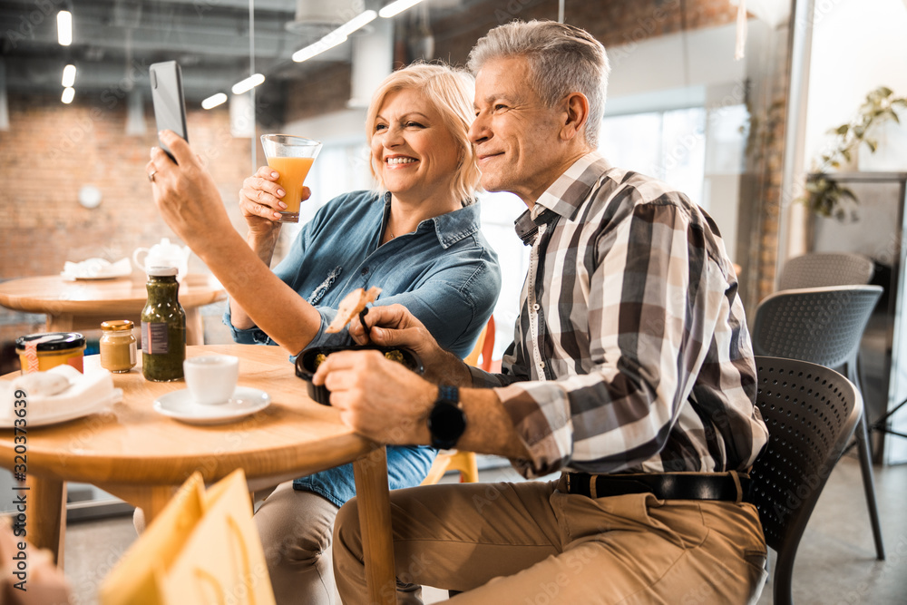 Smiling mature man and woman looking at phone camera Smiling mature man and woman looking at phone camera