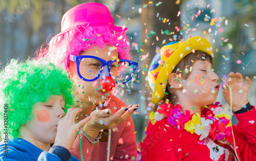 Fotografia a mother and her children are playing with confetti in carnival costume