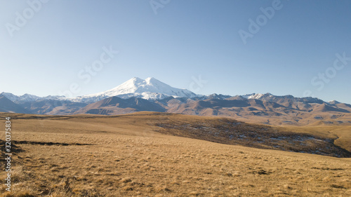Beautiful landscape: desert highlands in autumn. View of mount Elbrus. Dry grass, rocks, mountains. Trip to the Caucasus in Russia