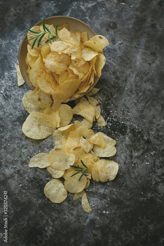 Crispy potato chips in the bowl with salt and seasonings