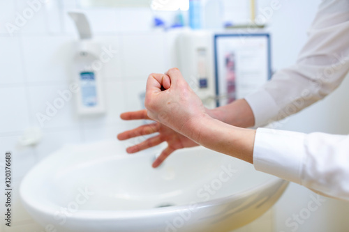 A nurse disinfects her hands in a hospital room