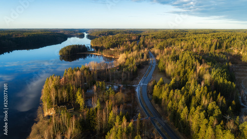 Aerial view from drone on road, forest and lake. Sunset time. Finland, Nuuksio.