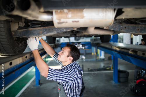 Portrait of mechanic repairing a lifted car