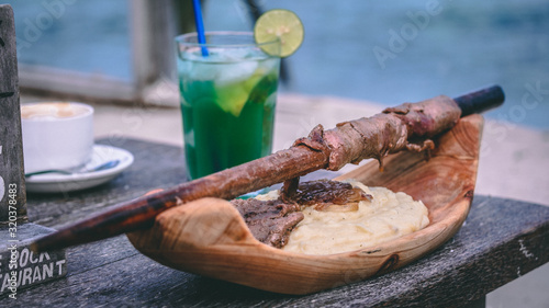 Pingwe, Zanzibar, Tanzania 30.12.2019 - Beef with potatoes in The Rock restaurant with a cocktail in the background photo
