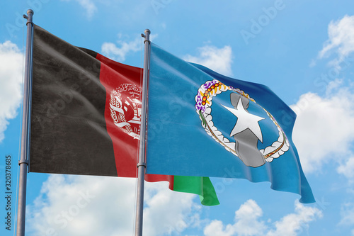 Northern Mariana Islands and Afghanistan flags waving in the wind against white cloudy blue sky together. Diplomacy concept, international relations.