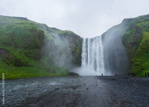 Majestic skogafoss in Iceland, cloudy day with tourists in front